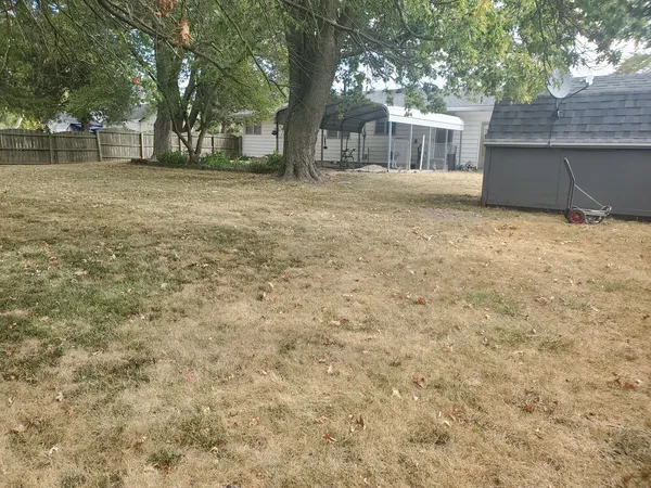 a backyard of a house with large trees and brick wall