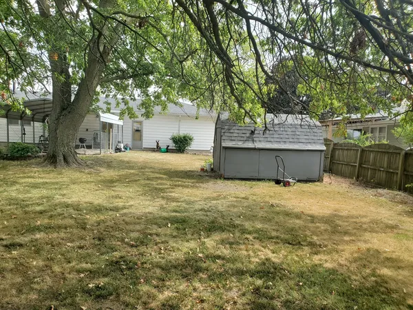 a view of backyard with large trees and wooden fence