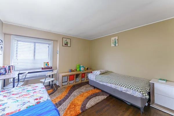 a bedroom with two beds and potted plants with wooden floor