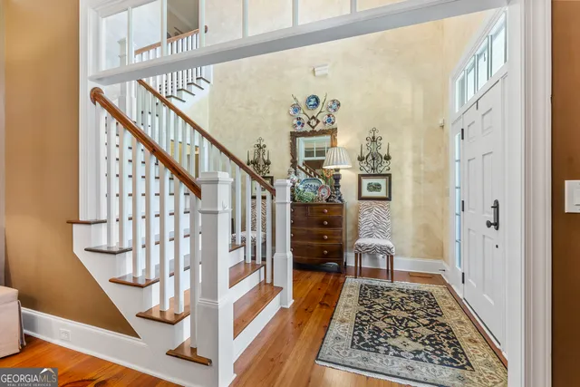 a kitchen with stainless steel appliances granite countertop a refrigerator a stove top oven a sink dishwasher and white cabinets with wooden floor