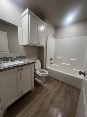 a bathroom with a granite countertop sink a toilet and bathtub