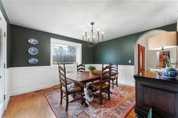 a dining room with chandelier fan and wooden floor
