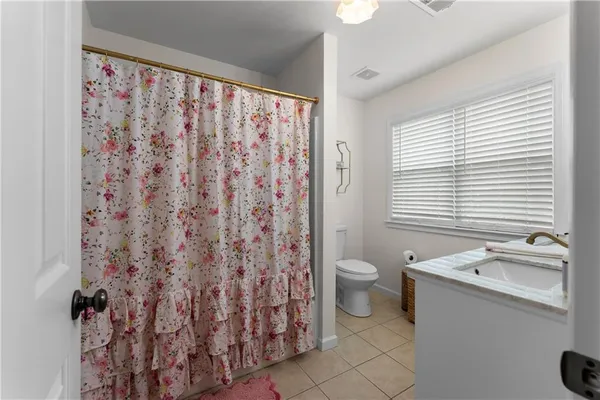 a bathroom with a granite countertop toilet a sink and a window