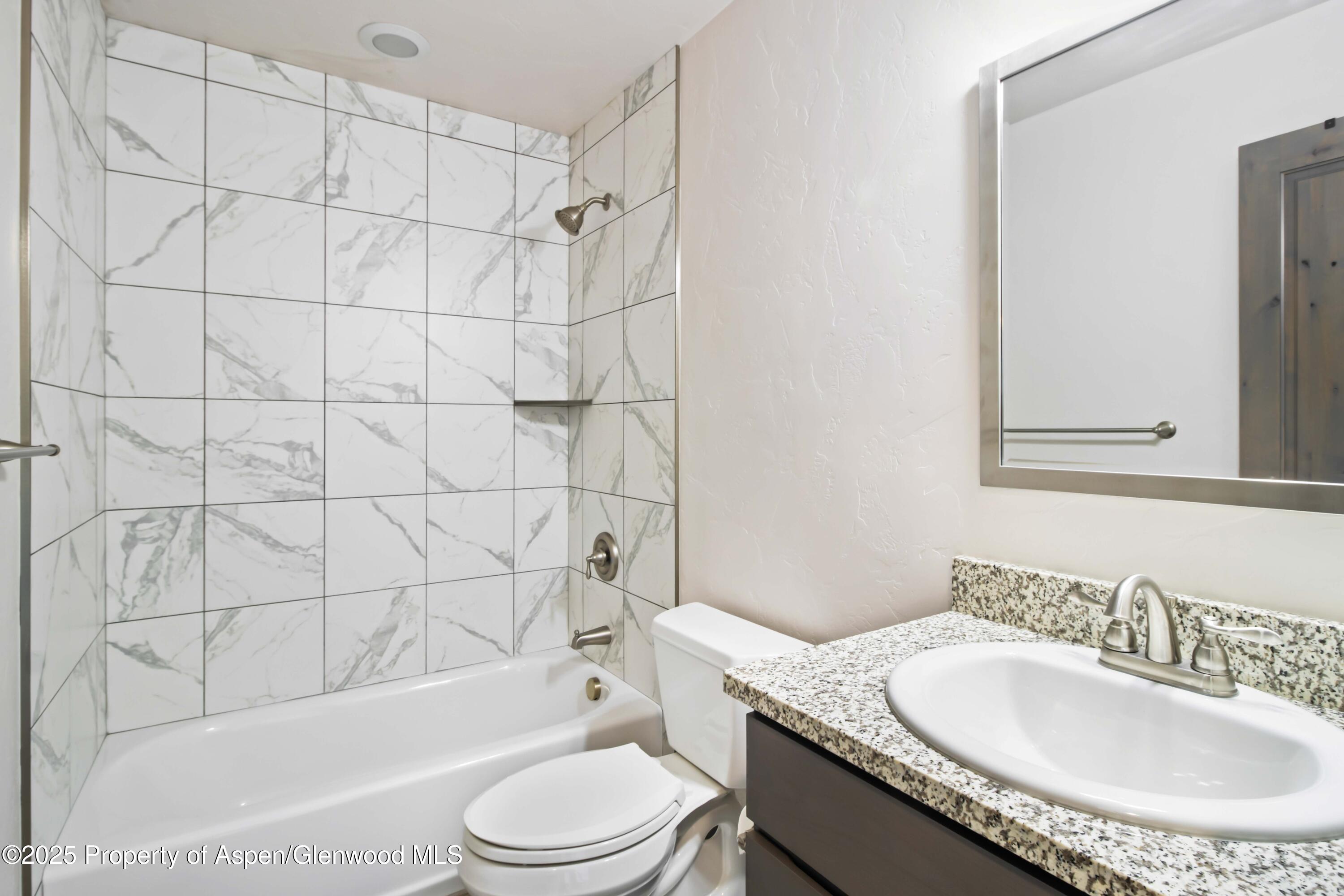 123 Redstone Drive New Castle, CO 81647 - Photo 27 of 34 a bathroom with a granite countertop sink toilet mirror and bathtub