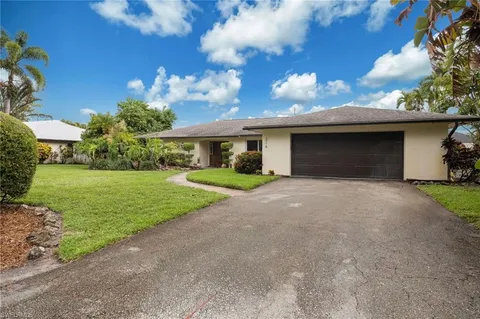 a view of a house with a yard and palm trees