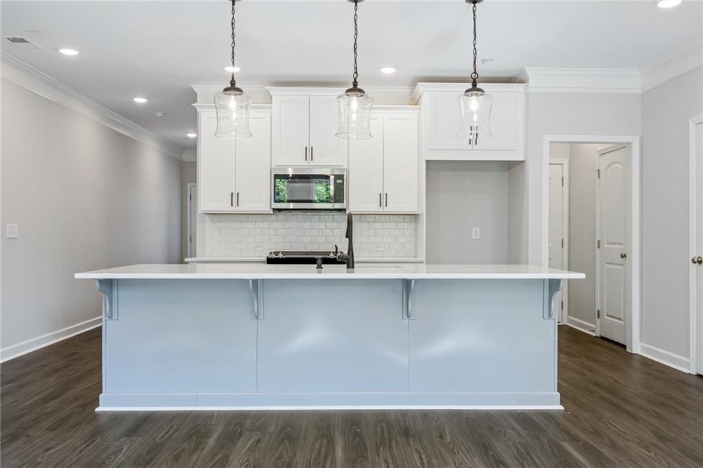 3744 Silvery Way Powder Springs, GA 30127 - Photo 7 of 26 a large kitchen with stainless steel appliances a large counter top a stove a refrigerator and a wooden floors