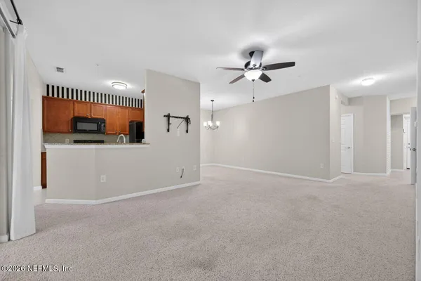 an empty room with windows and chandelier fan