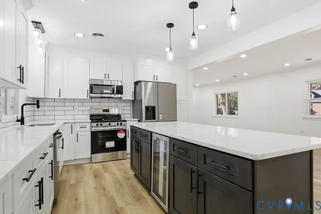 a kitchen with kitchen island granite countertop appliances cabinets and a sink