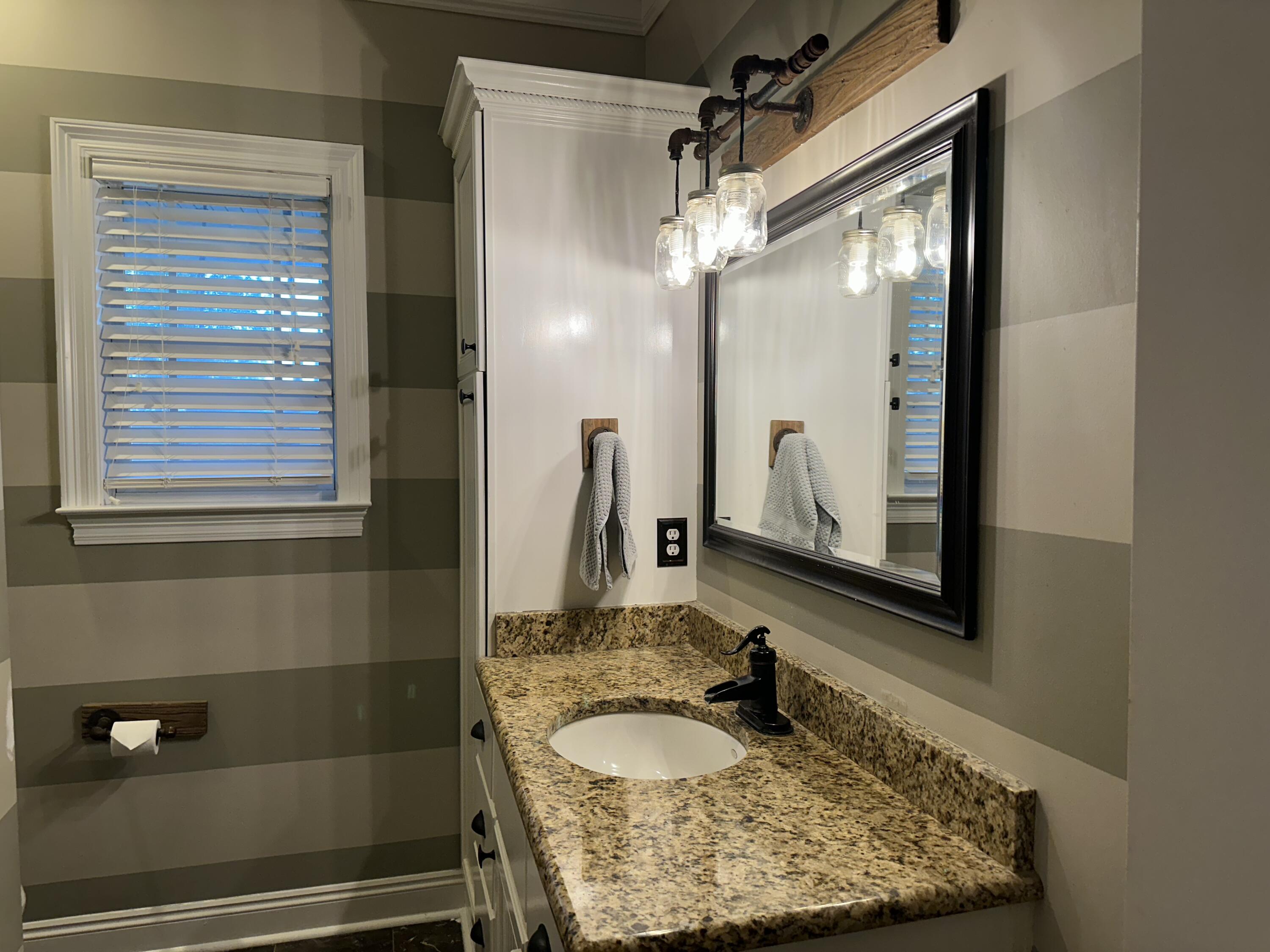 7935 Peacock Road Baker, FL 32531 - Photo 17 of 20 a bathroom with a granite countertop sink a mirror and shower