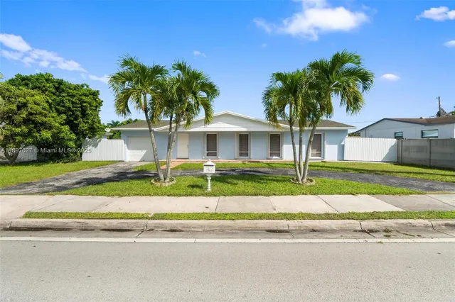 a front view of a house with a yard and palm trees