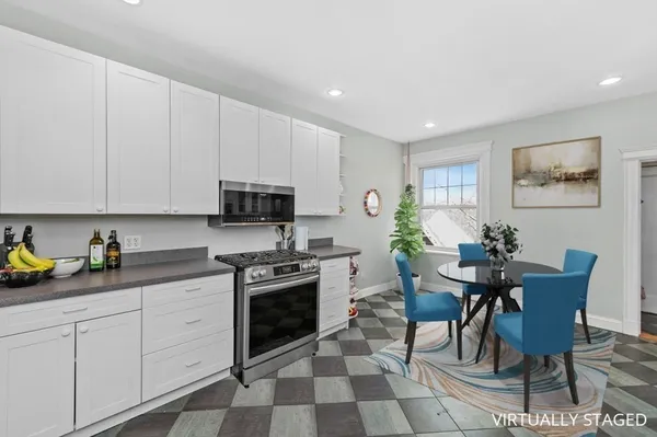 a kitchen with stainless steel appliances granite countertop a stove a sink a microwave a dining table and chairs with white cabinets