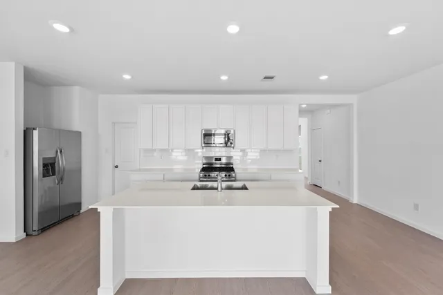 a kitchen with kitchen island white cabinets and stainless steel appliances