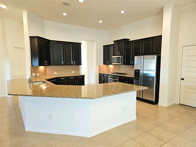 a large kitchen with a large counter top stainless steel appliances and cabinets