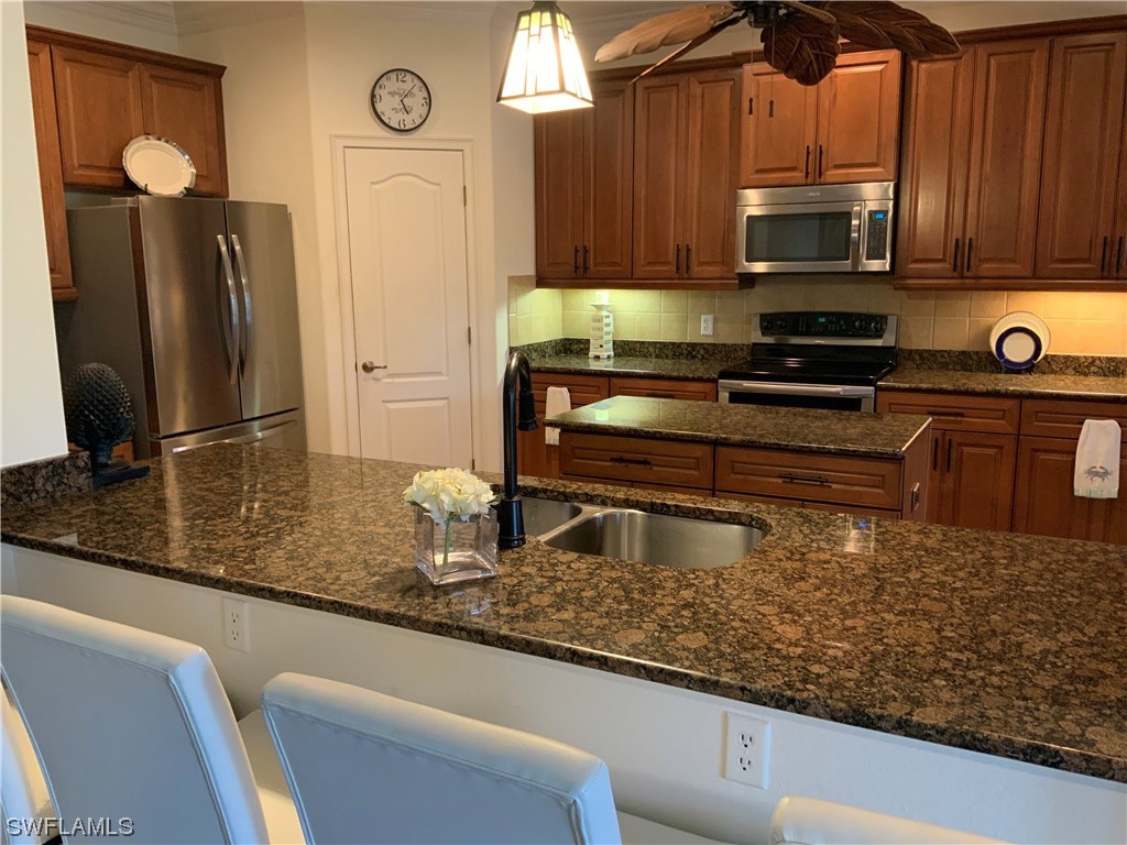 12918 Pastures Way Fort Myers, FL 33913 - Photo 8 of 34 a kitchen with kitchen island granite countertop a sink a stove and a microwave