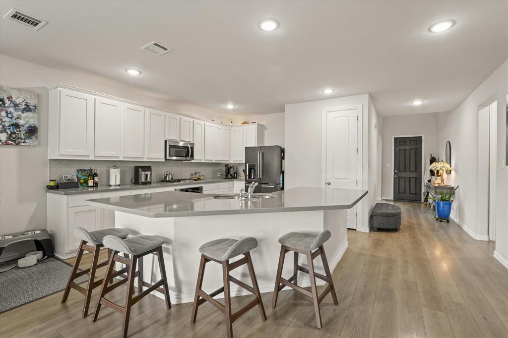 3217 Flowering Peach Dr. Heath, TX 75126 - Photo 7 of 30 a kitchen with stainless steel appliances granite countertop a stove top oven a refrigerator a sink and white cabinets with wooden floor