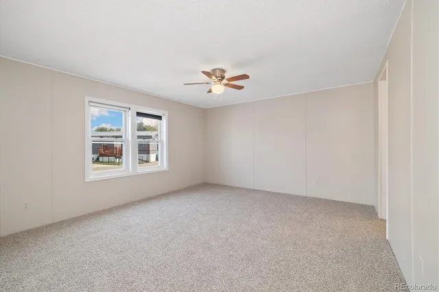 an empty room with a window and a ceiling fan