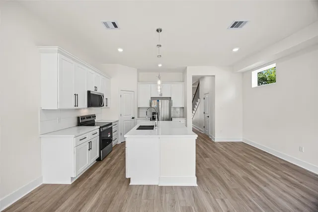 a large kitchen with stainless steel appliances kitchen island a stove a sink dishwasher and a refrigerator with wooden floor