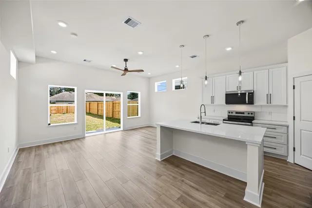 a large kitchen with stainless steel appliances granite countertop a stove and a wooden floors