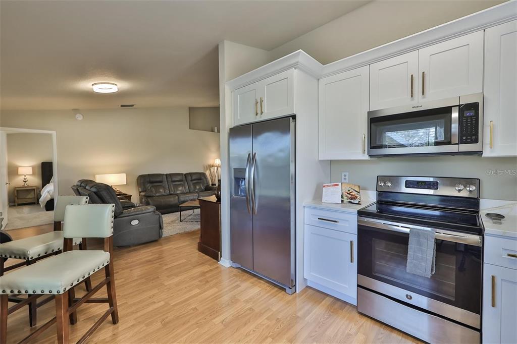 128 Lookout Drive Apollo Beach, FL 33572 - Photo 16 of 36 a kitchen with stainless steel appliances kitchen island granite countertop a refrigerator stove and microwave