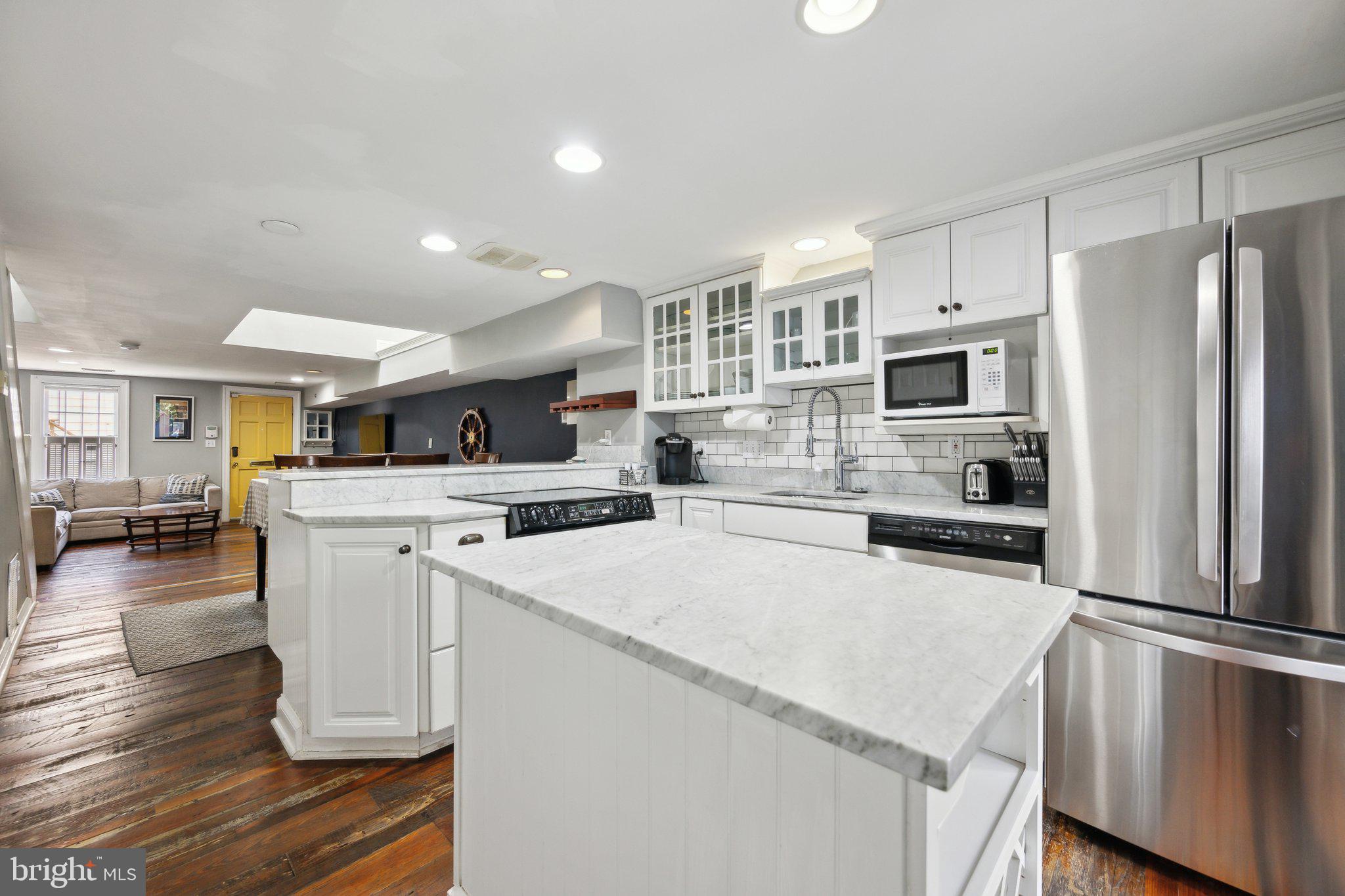 24 Fleet Street Annapolis, MD 21401 - Photo 9 of 32 a kitchen with a refrigerator a stove top oven a sink dishwasher and white cabinets with wooden floor