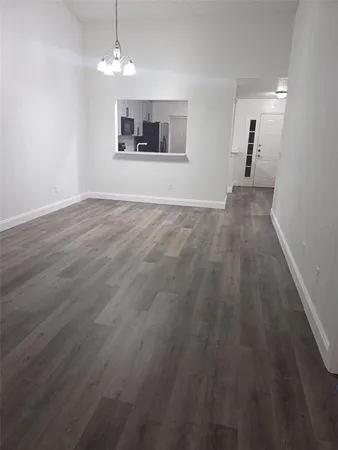 an empty room with wooden floor and a ceiling fan