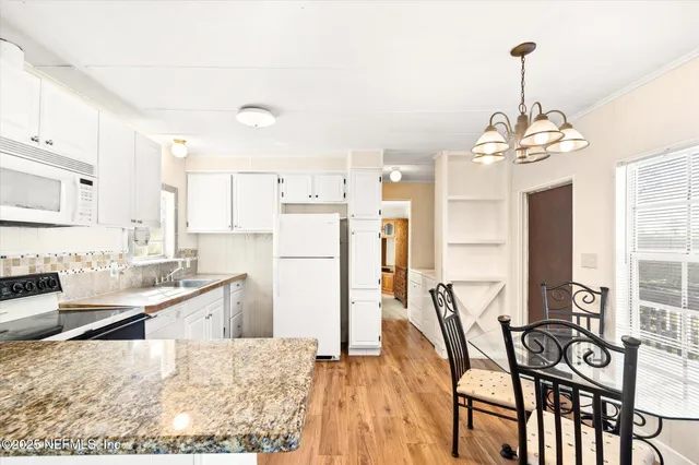 a kitchen with stainless steel appliances kitchen island granite countertop a refrigerator a stove and a wooden floors
