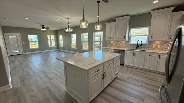 a kitchen with kitchen island granite countertop a sink and refrigerator