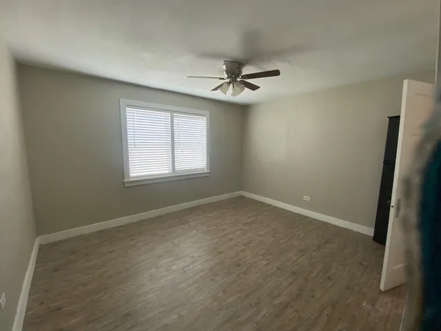an empty room with a window and a fan
