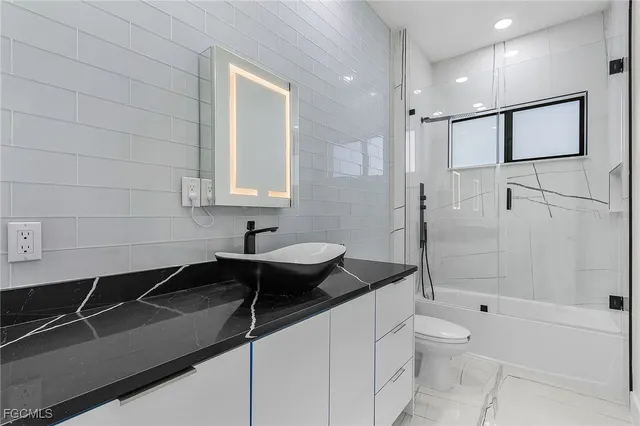 a bathroom with a granite countertop sink a toilet a mirror and shower