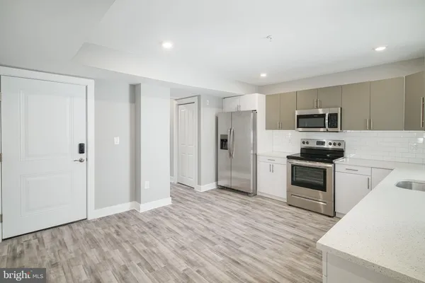 a kitchen with granite countertop a refrigerator and a stove top oven