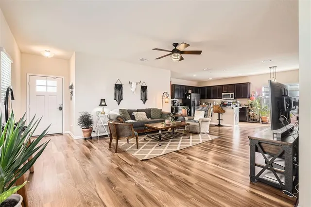 a living room with furniture kitchen view and a wooden floor
