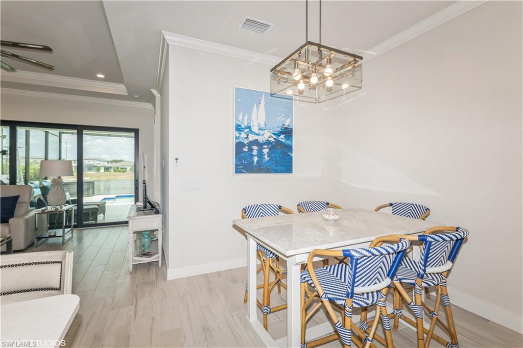 14605 Kingfisher Loop Naples, FL 34120 - Photo 11 of 42 a view of a dining room with furniture a chandelier and wooden floor