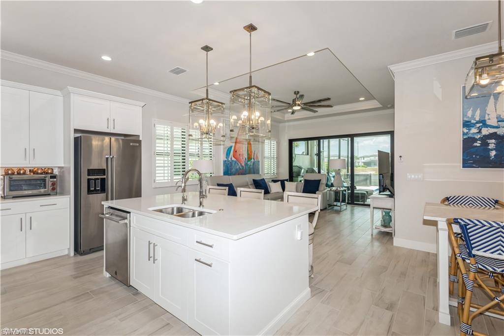 14605 Kingfisher Loop Naples, FL 34120 - Photo 14 of 42 a large kitchen with kitchen island a large counter space a sink appliances and living room view
