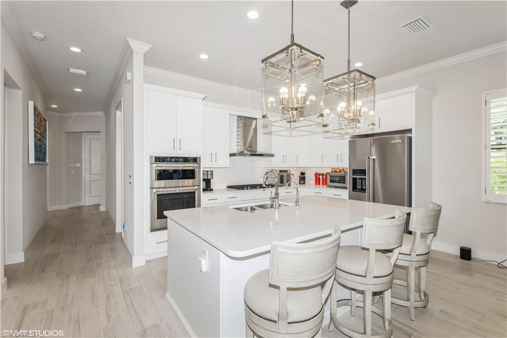 14605 Kingfisher Loop Naples, FL 34120 - Photo 15 of 42 a kitchen with stainless steel appliances a table and chairs in it