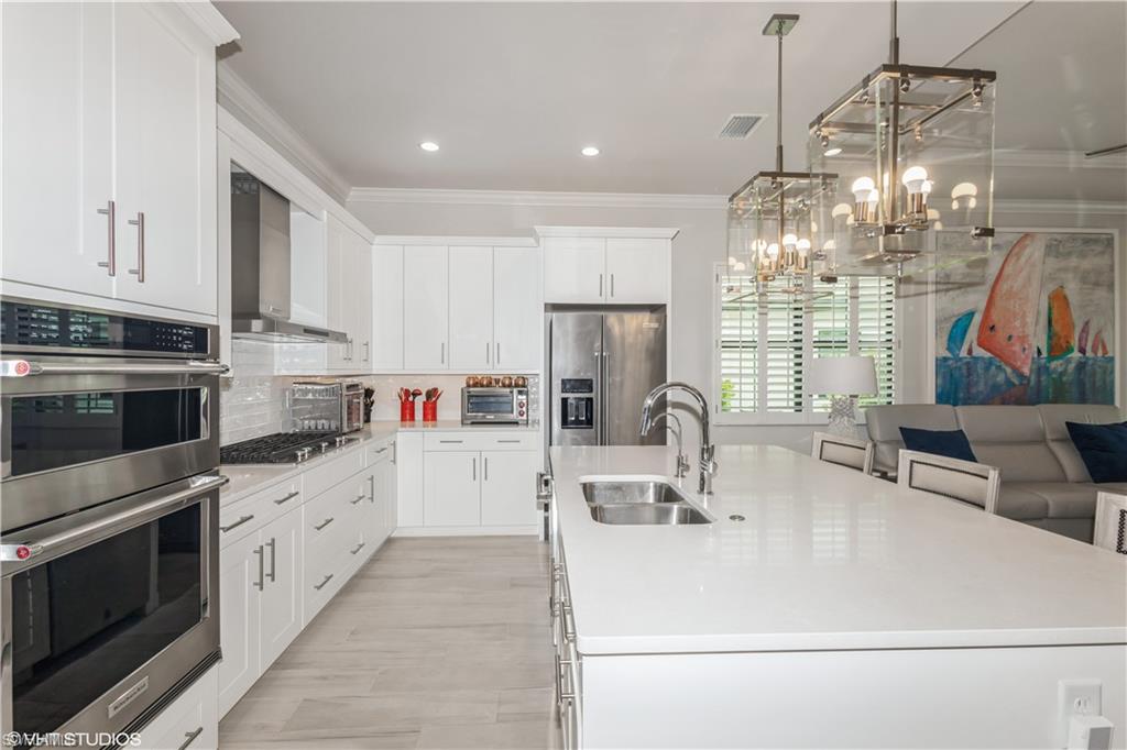 14605 Kingfisher Loop Naples, FL 34120 - Photo 7 of 42 a kitchen with kitchen island granite countertop a sink cabinets and stainless steel appliances