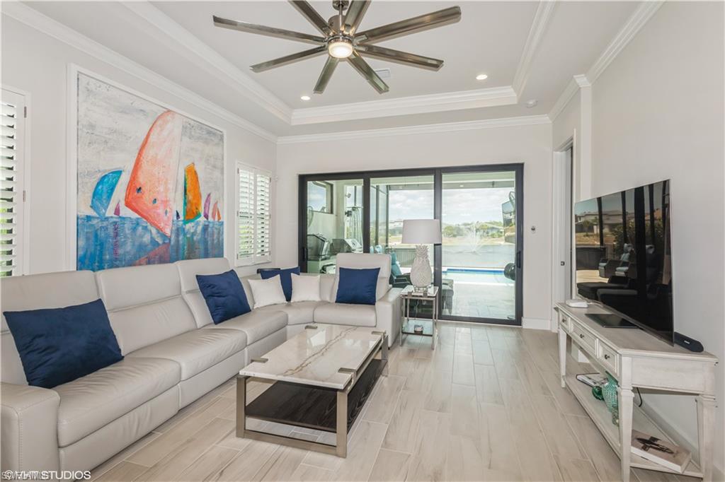 14605 Kingfisher Loop Naples, FL 34120 - Photo 8 of 42 a living room with furniture a flat screen tv and a floor to ceiling window