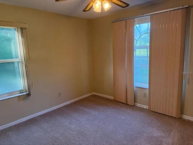 an empty room with a chandelier fan and windows