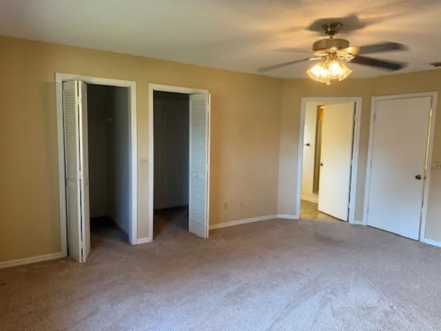 a view of an empty room with a chandelier fan