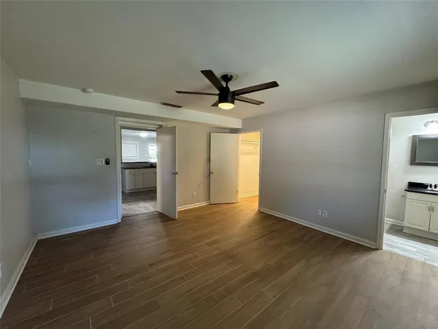 an empty room with wooden floor and a ceiling fan