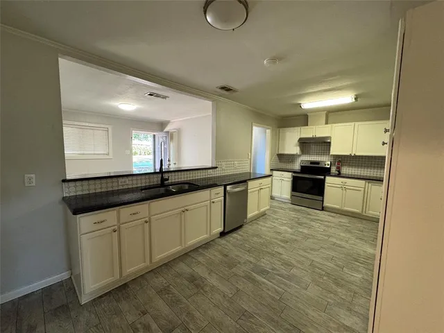 a large kitchen with granite countertop a large counter top stainless steel appliances and cabinets