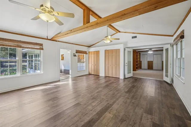 a view of an empty room with window and wooden floor
