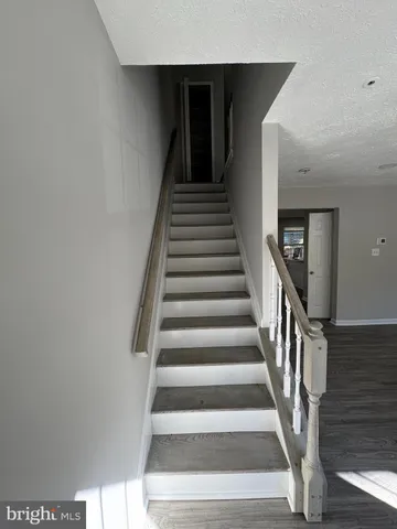 a view of staircase with wooden floor and white walls