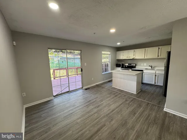 a view of a kitchen with wooden floor electronic appliances and windows