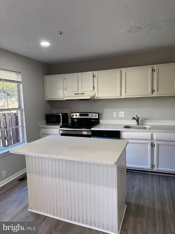 a kitchen with stainless steel appliances granite countertop a stove a sink a refrigerator and white cabinets