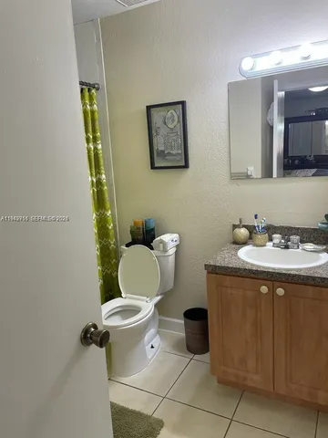 a bathroom with a granite countertop toilet sink and mirror