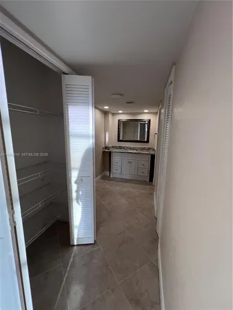 a view of a refrigerator in kitchen and an empty room