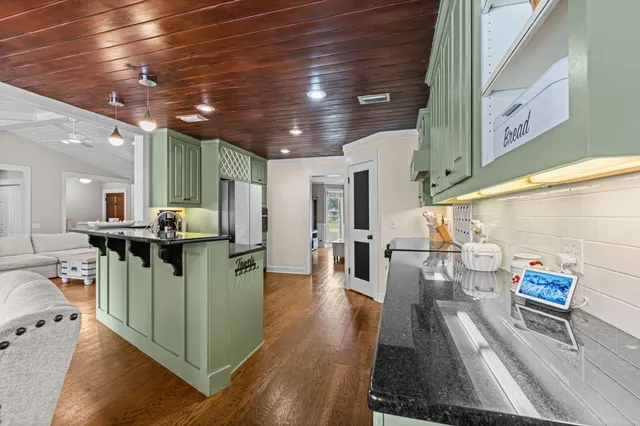 a kitchen with stainless steel appliances kitchen island granite countertop a table chairs and a wooden floor