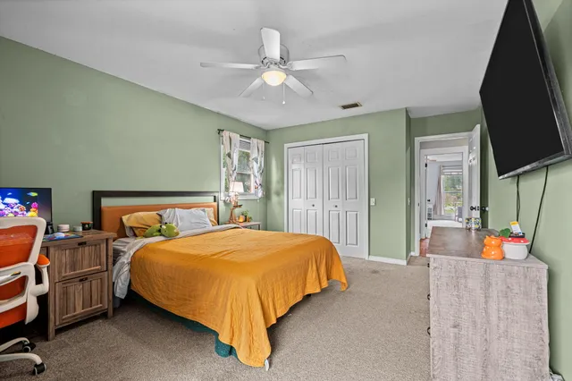 a bedroom with a bed and a flat tv screen on dresser
