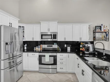 a kitchen with granite countertop a sink and white cabinets