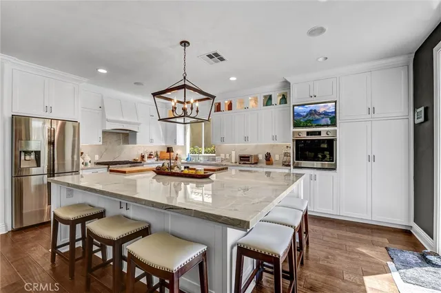 a kitchen with stainless steel appliances granite countertop a sink a stove a refrigerator cabinets and chairs